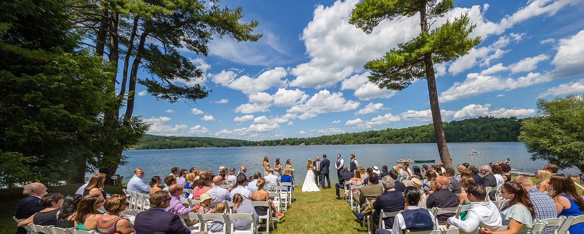 wedding on grassy field in front of a lake